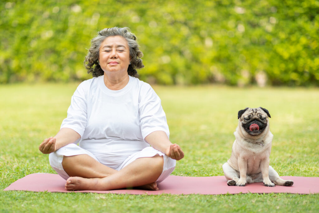 Portrait Of Woman With Dog Sitting On Grass