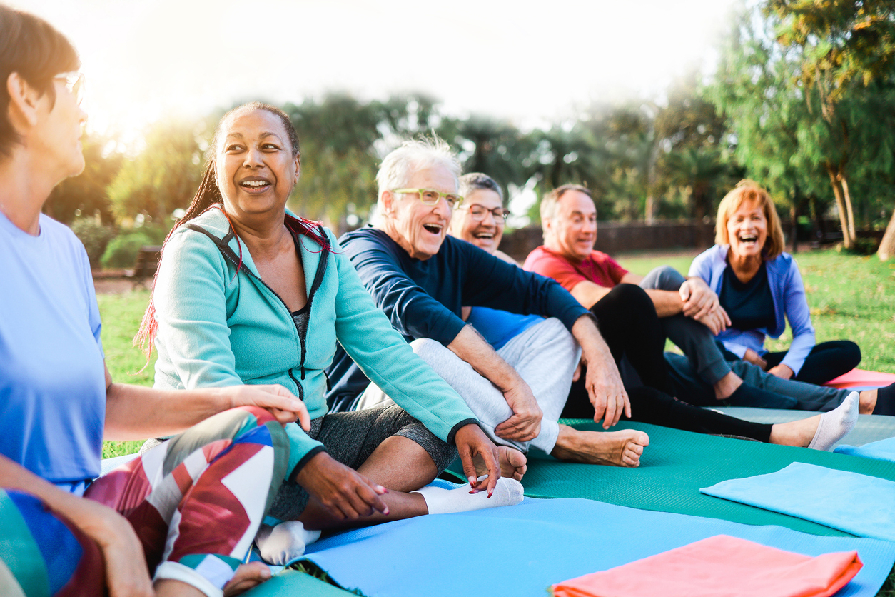Happy senior people after yoga sport class having fun sitting outdoors in park city Happy senior people after yoga sport class having fun sitting outdoors in park city