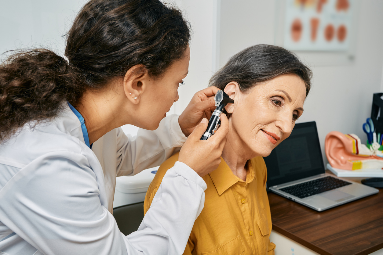 Hearing exam for elderly citizen people. Otolaryngologist doctor checking mature woman's ear using otoscope or auriscope at medical clinic Hearing exam for elderly citizen people. Otolaryngologist doctor checking mature woman's ear using otoscope or auriscope at medical clinic